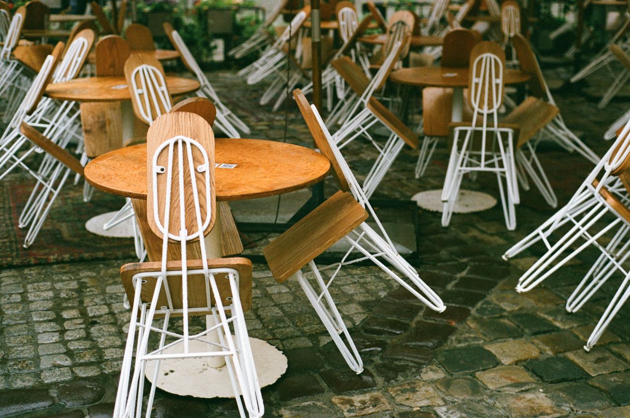 heros-img A scenic view of empty wooden tables and chairs in a cobblestone cafe setting in Lviv.