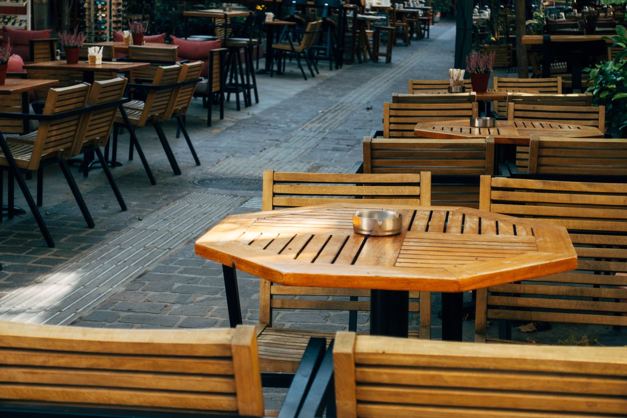 about-us A cozy outdoor café scene with wooden tables and chairs, perfect for dining or coffee.